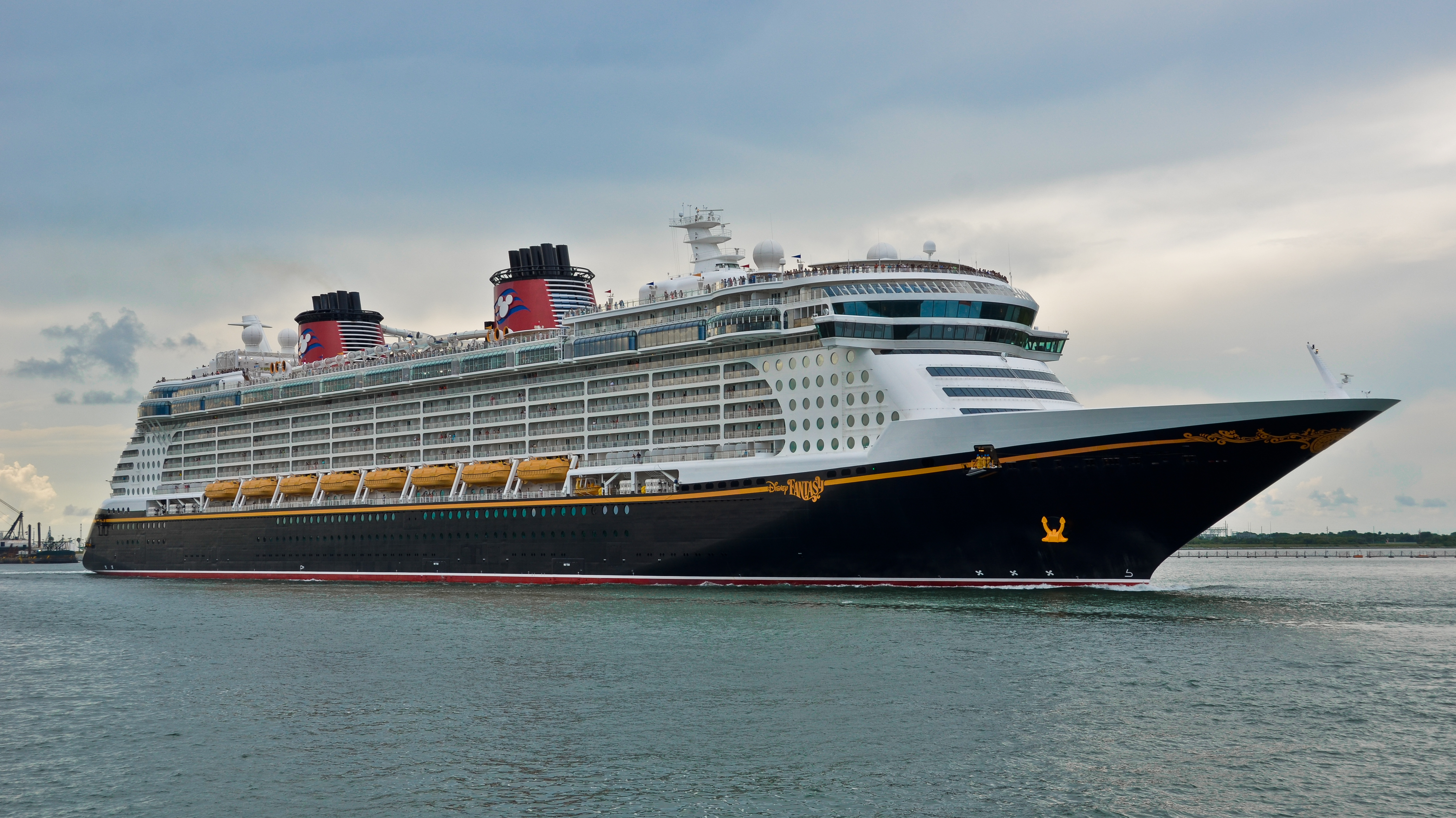 A large cruise ship docked at a terminal at Port Canaveral on a clear morning.